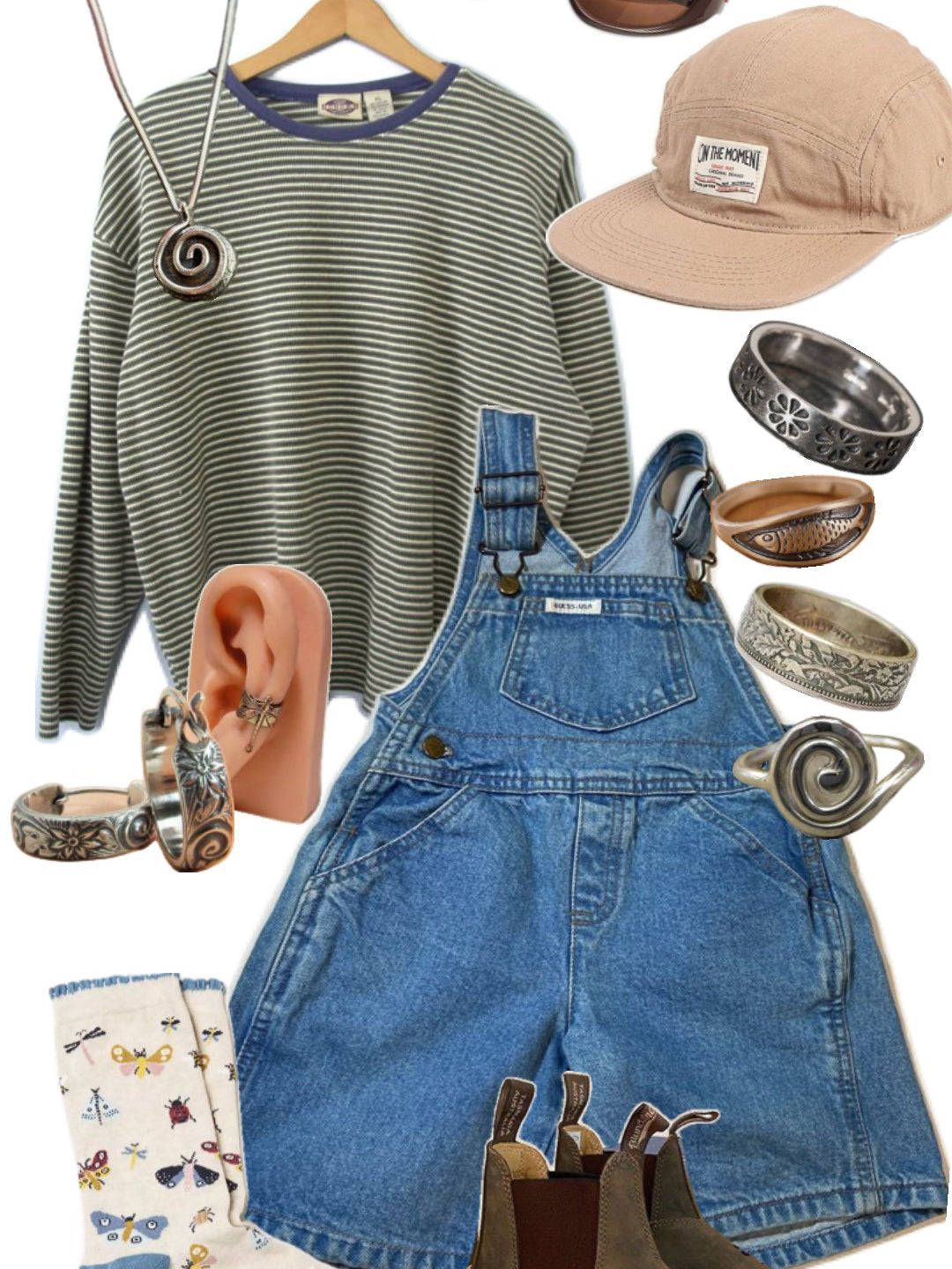 Earthy eclectic flat lay: striped olive long sleeve, denim overall shorts, corduroy cap, silver rings, brown boots.