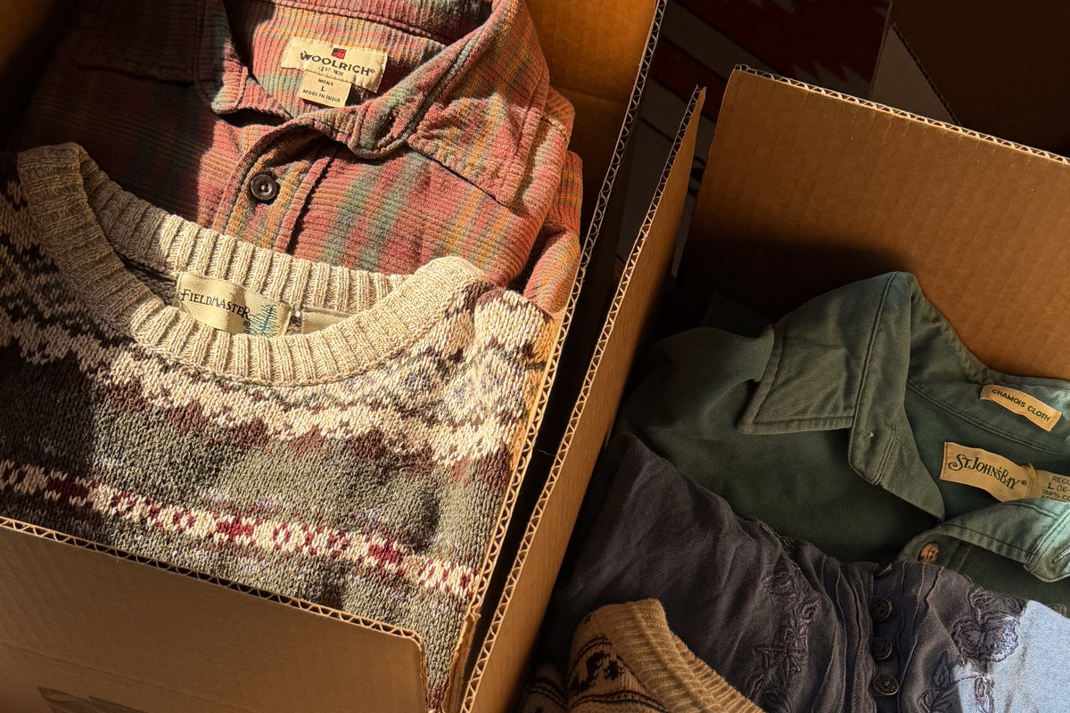 Fair isle sweater, plaid shirt and an olive corduroy jacket packed together in a Forager's Goods box