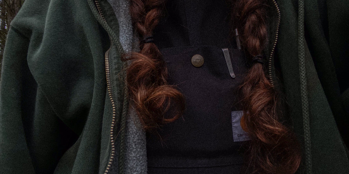 Dark green fleece zip up layered over a black canvas jacket, granola aesthetic layering in forest tones